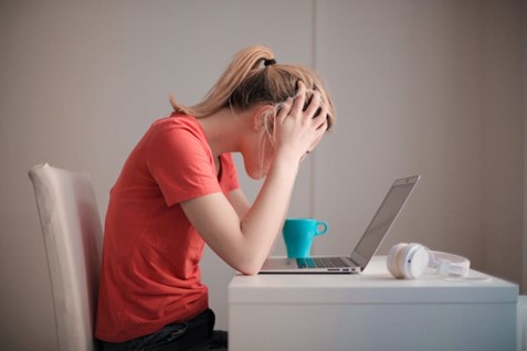 Femme qui se prend la tête entre les mains devant son ordinateur