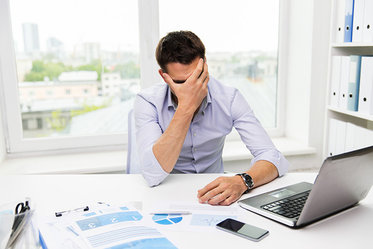 homme au travail qui se prend la tête dans les mains