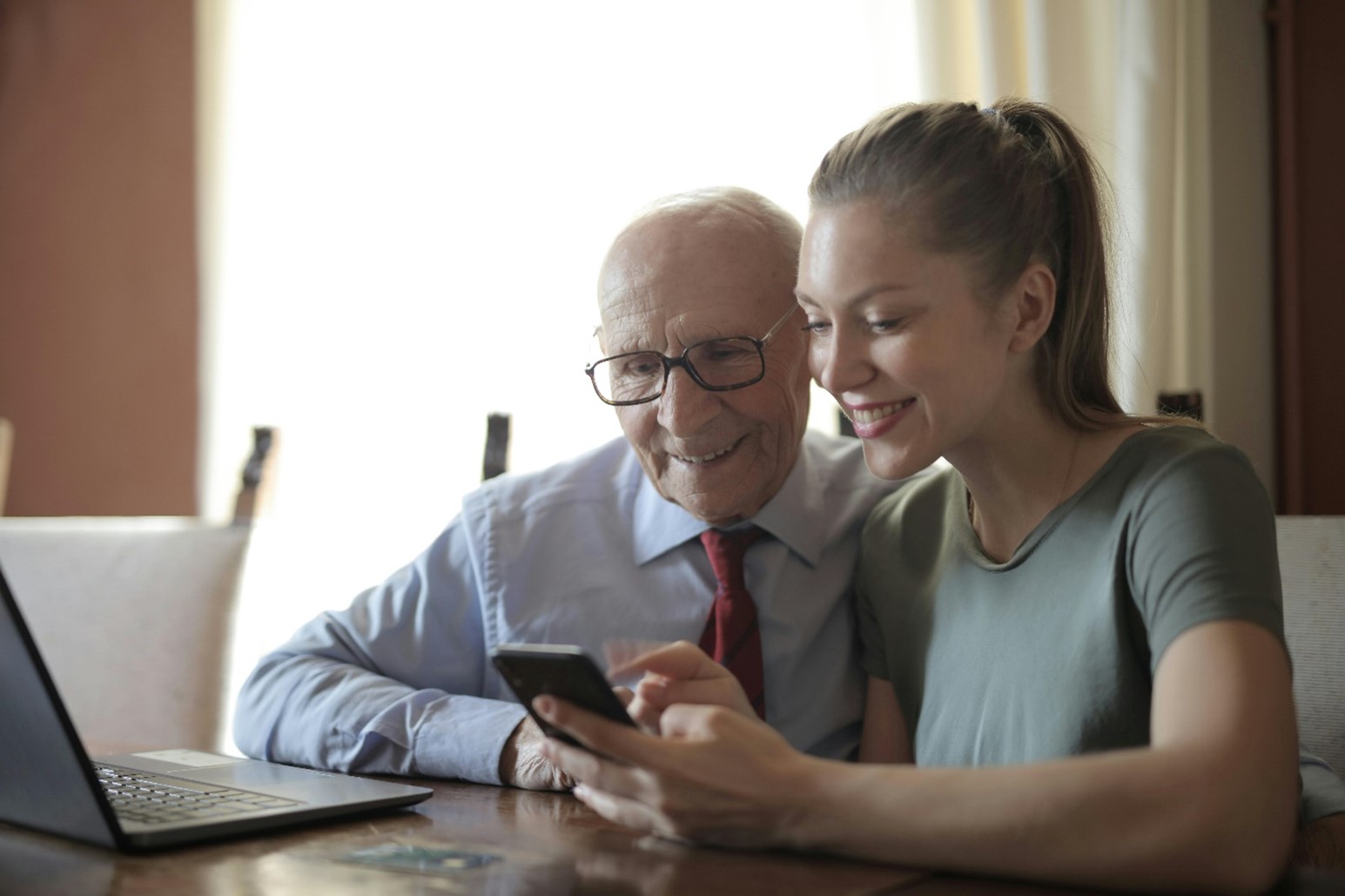 homme âgé et jeune femme devant un téléphone