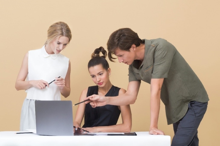 3 personnes regardent l'écran d'un ordinateur portable