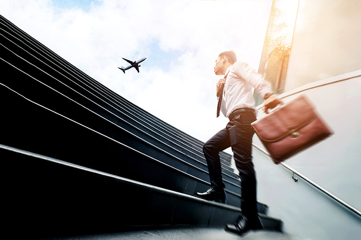 Homme avec une valise dans l'escalier avec un avion en arrière plan