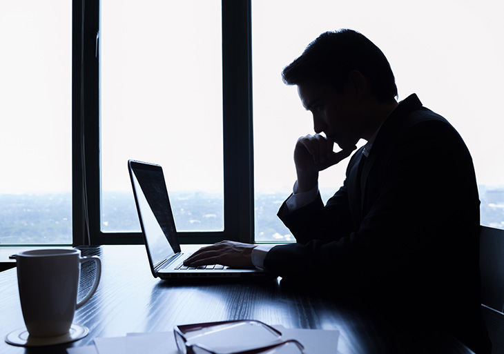 homme devant son ordinateur avec une tasse de café