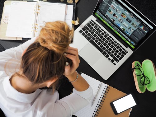 femme se tenant la tête devant ordinateur